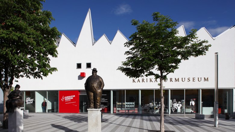 Karikaturmuseum Krems, © Karikaturmuseum Krems/Christian Redtenbacher Außenansicht des Karikaturmuseums Krems mit Statuen und Bäumen.