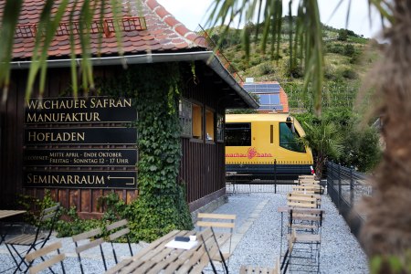 Die Wachaubahn steht im Bahnhof Dürnstein. Im Vordergrund ist das Gebäude der Safranmanufaktur zu sehen