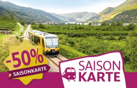 Aktion Saisonkarte, © NÖVOG/Schwarz-König Ein Zug fährt durch eine grüne Landschaft mit Hügeln im Hintergrund. Ein Banner zeigt 50% Rabatt auf eine Saisonkarte an.