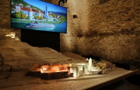Ausstellung im Stift Dürnstein, © Weinfranz Modell von Dürnstein mit beleuchtetem Stift und Foto im Hintergrund.