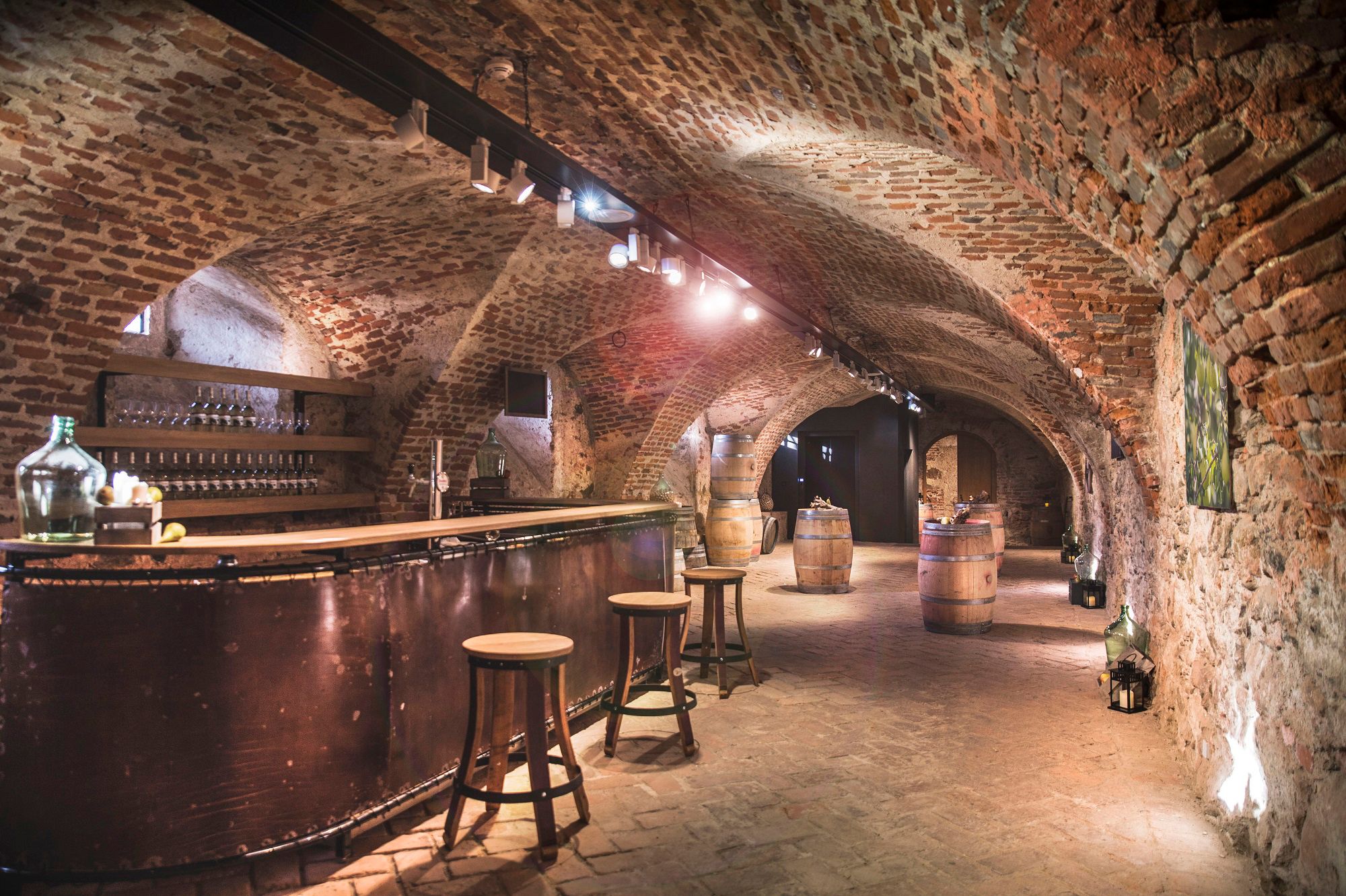 Historischer Schlosskeller mit Backsteinwänden, Bar und Holzfässern.