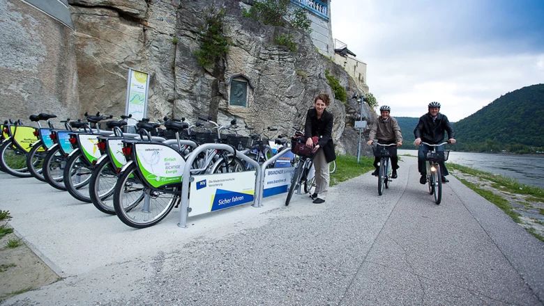 Radfahrende an einer Nextbike-Verleihstation direkt an der Donau.