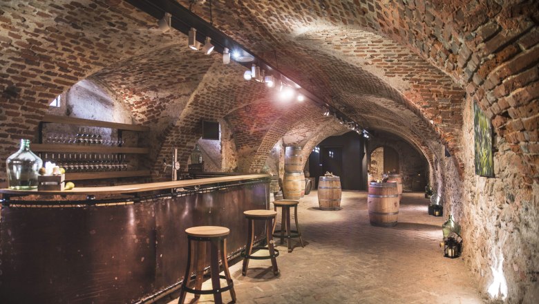 Historischer Schlosskeller mit Backsteinwänden, Bar und Holzfässern.