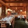 Cozy restaurant with wooden walls, covered tables and fireplace.