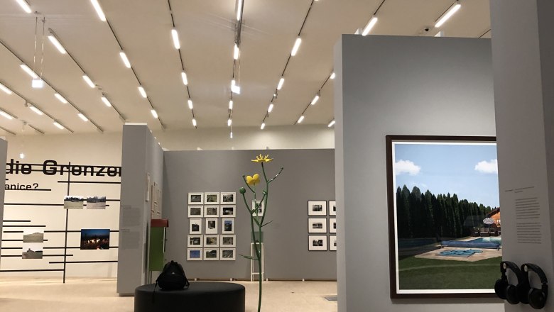 Interior view of a modern gallery with works of art on the walls and a sculpture in the center.