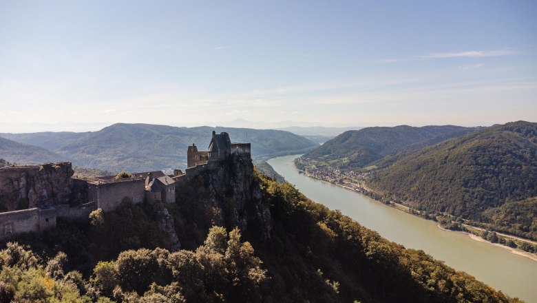 Luftaufnahme der Burgruine Aggstein mit Blick auf die Donau und umliegende H&uuml;gel.