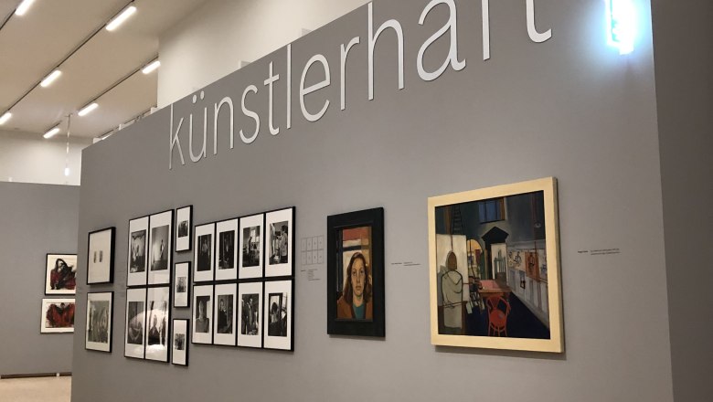 Exhibition wall with works of art and the lettering 'künstlerhaft'.