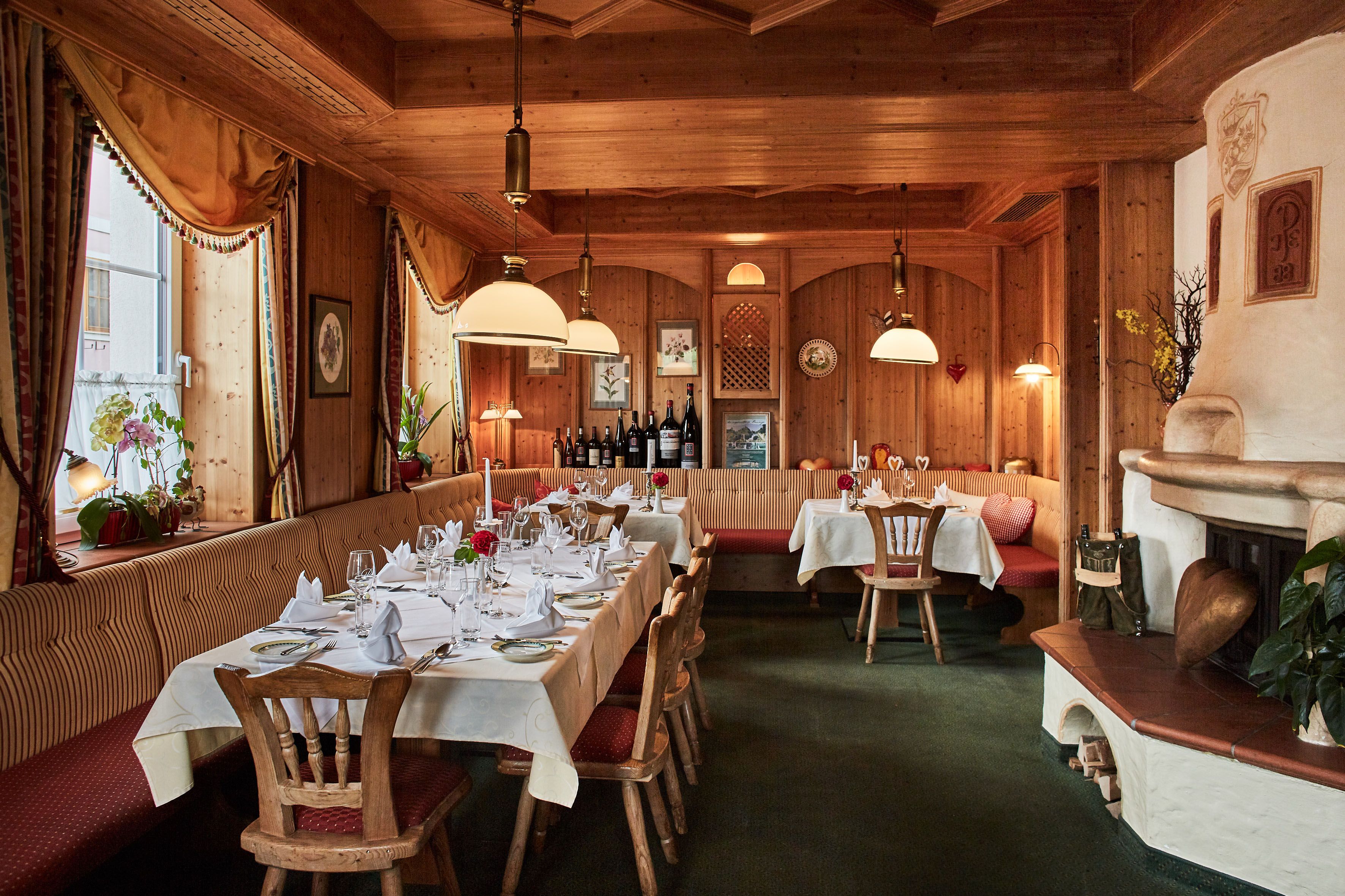 Gemütliches Restaurant mit Holzwänden, gedeckten Tischen und Kamin.