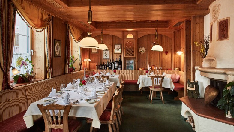 Gemütliches Restaurant mit Holzwänden, gedeckten Tischen und Kamin.