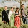 Familie Pichler  in traditioneller Kleidung stehen im Freien vor einem Baum, im Hintergrund ist Sift Melk zu sehen