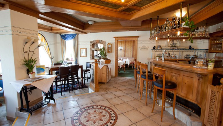 Gemütliche Hotelbar mit Holzmöbeln und dekorativem Fliesenboden.