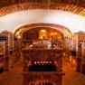 An atmospherically lit wine cellar with brick walls and wine bottles on shelves.